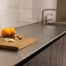Stainless steel countertop beside a wooden cutting board with oranges and spices in a contemporary kitchen.